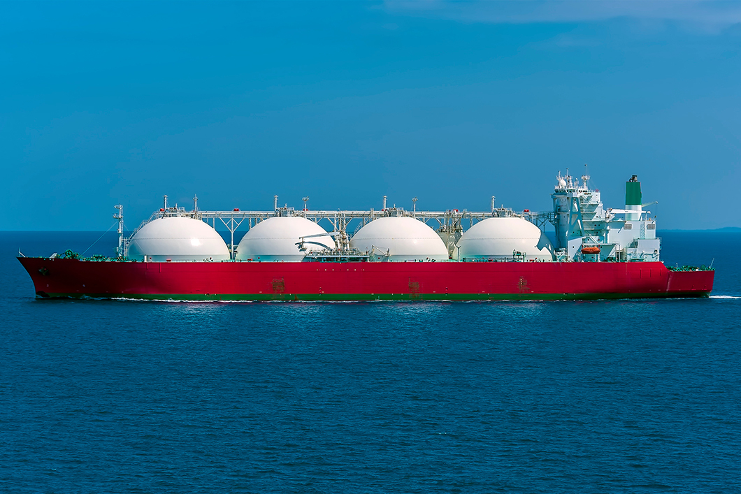Flüssigwasserstoff: Innovative Speicher sollen vierzigfache Kapazität und 80 Prozent Kostenreduktion ermöglichen Ein Schiff mit rotem Rumpf und vier großen weißen Tanks.