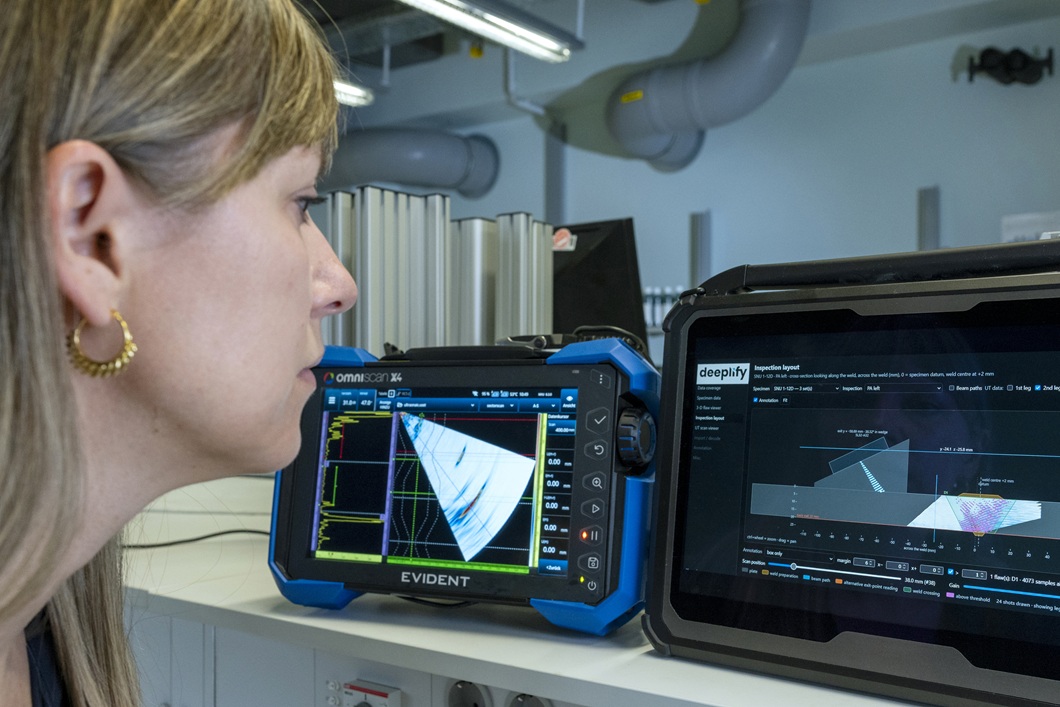 Pr&uuml;fpersonal wertet Ultraschalldaten an einem mobilen Pr&uuml;fger&auml;t und einem Computerbildschirm aus. Die Darstellungen unterst&uuml;tzen bei der Erkennung und Bewertung von Materialfehlern, etwa Sch&auml;den in Schwei&szlig;n&auml;hten.