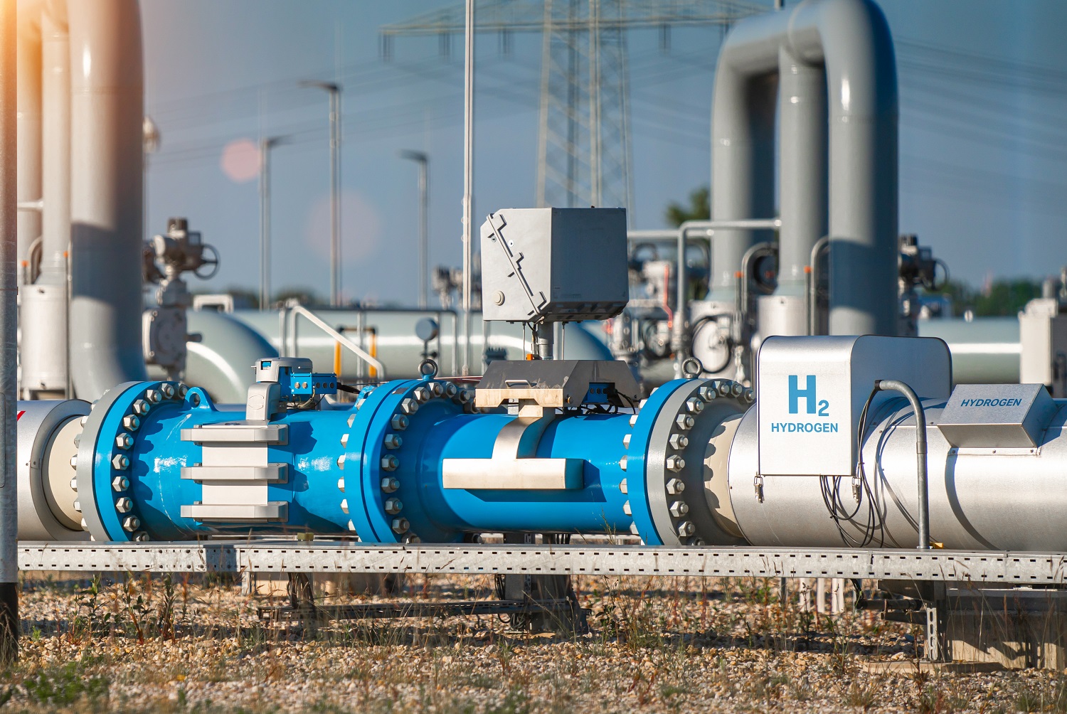 Wasserstoffabhängige mechanische Eigenschaften der Schweißnahtgefüge niedriglegierter Stähle für Ferngasleitungen Eine Stahlleitung für Wassersoff mit dem Aufdruck "H2 - Hydrogen" vor einer Hochspannungsleitung.