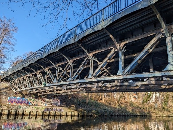Innovatives Instandsetzungsschweißen von Altstahl Eine von einer Stahlkonstruktion getragene Brücke, die über ein Flussbett verläuft.
