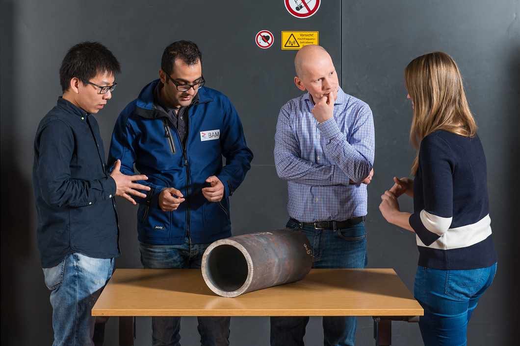 Das Team um Dr.-Ing. J&uuml;rgen Olbricht begutachtet ein angeliefertes St&uuml;ck einer Kraftwerks-Dampfleitung (v.l.n.r.: Dong Wang, Dr.-Ing. Hamed Ravash, Dr.-Ing. J&uuml;rgen Olbricht und Maria J&uuml;rgens).