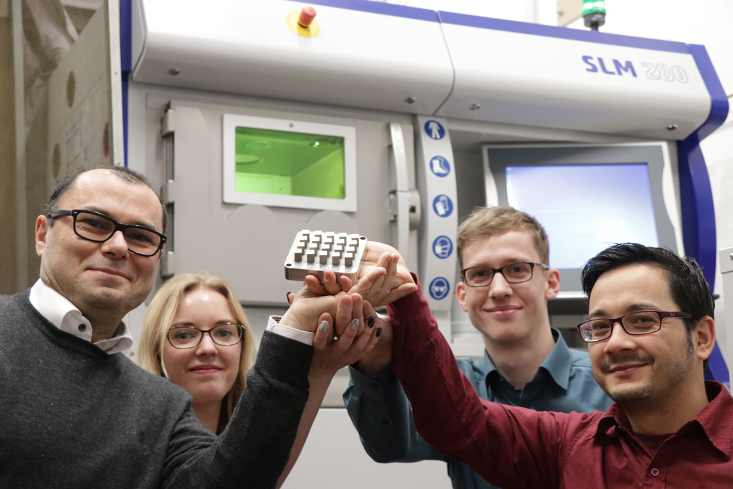 AGIL im Team: Prof. Giovanni Bruno mit den DoktorandInnen Tatiana Mishurova, Tobias Thiede, und Alexander Ulbricht vor der Anlage zum selektiven Laserschmelzen Prof. Dr. Bruno mit Mitarbeiter*innen
