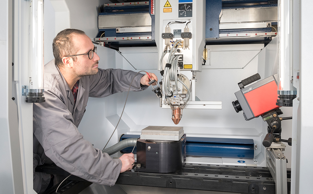 Justage der Fokusposition eines Aufbaus für die optische Emissionsspektroskopie an einer Anlage zum Laser-Pulver-Auftragsschweißen Mitarbeiter an einer Anlage zum Laser-Pulver-Auftragsschweißen