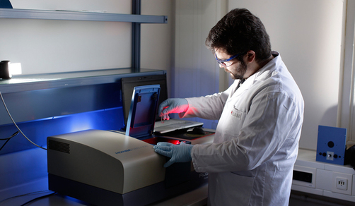 A BAM employee inserts a sample with fluorescence material into an analysis device