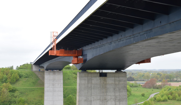 Eine Betonbrücke mit einer unten angebrachten Wartungsplattform.