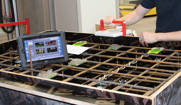 A BAM employee holds a reader device over sensors that are built into a steel grid for a concrete casing.
