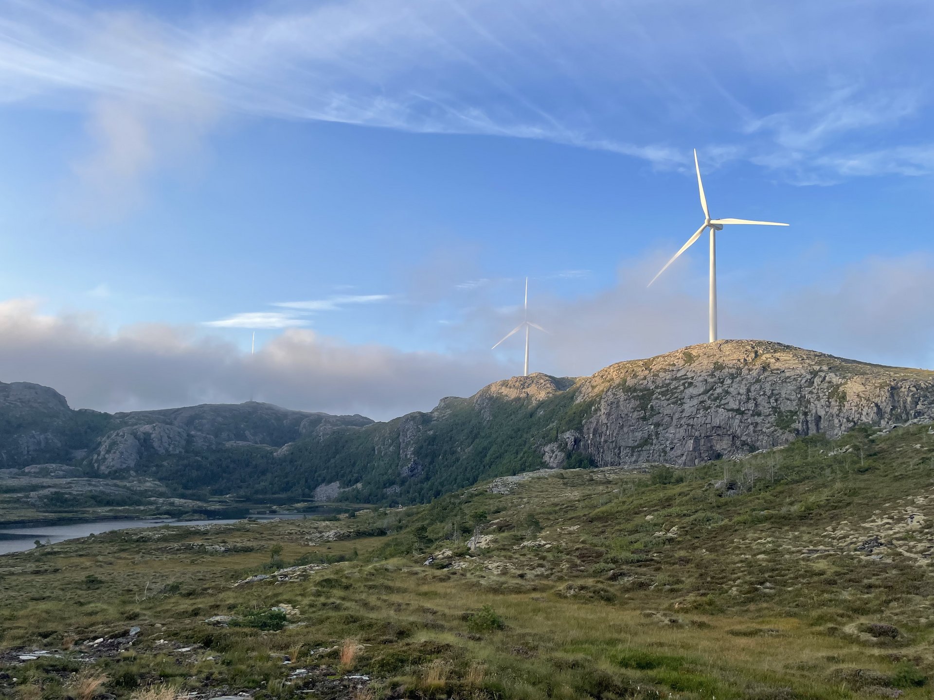 Zwei Windr&auml;der auf felsigen Bergen vor blauem Himmel und Wolken.