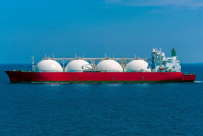 Ein Schiff mit rotem Rumpf und vier gro&szlig;en wei&szlig;en Tanks.