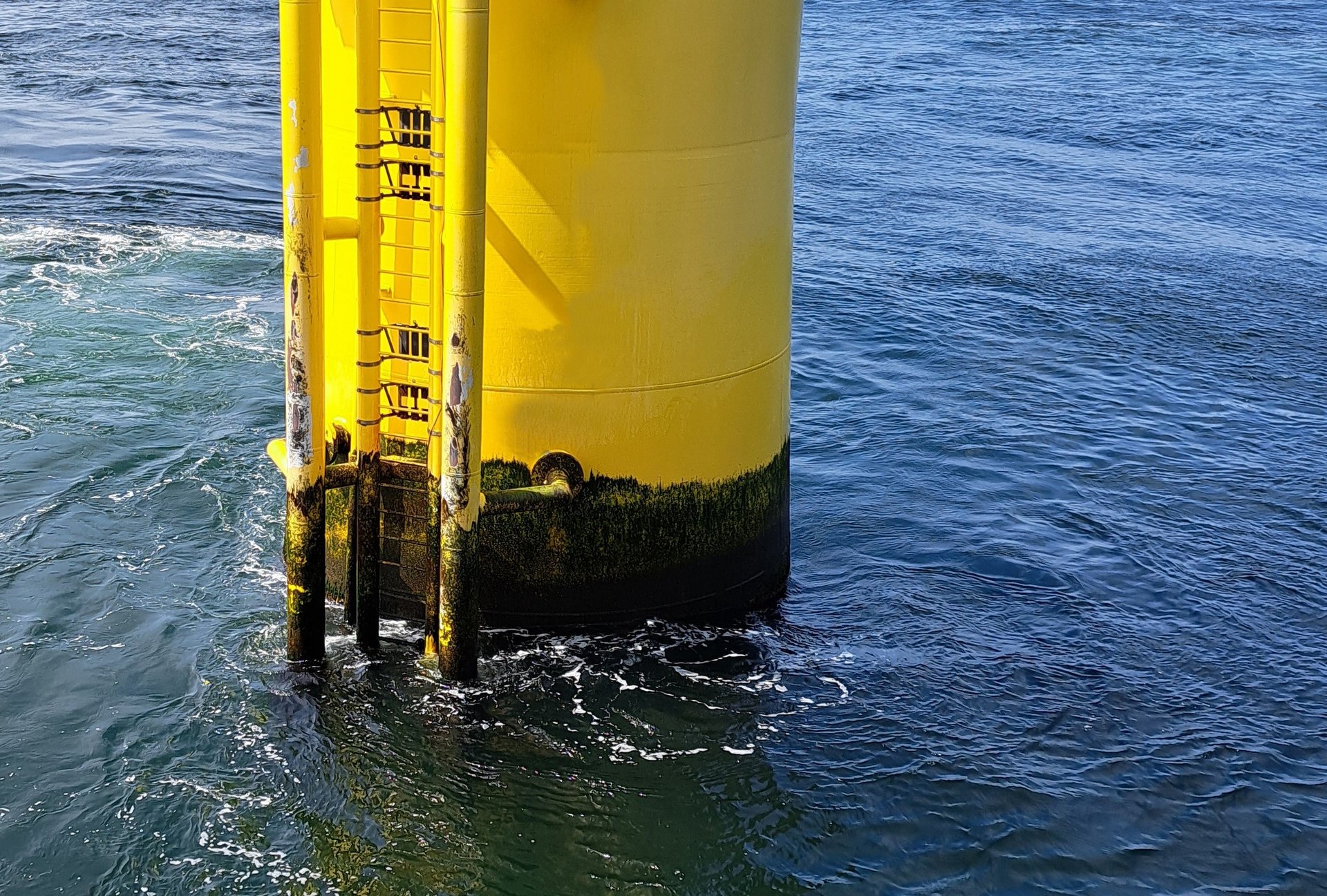 Nanopflaster - Steigerung der Lebensdauer und Reduktion der Lebensdauerkosten von Offshore-Windenergieanlagen durch Nanopflaster Im Meerwasser stehender, gelber Sockel einer Offshore-Windenergieanlage