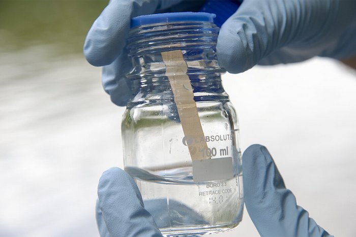 Paper of the month 09/2023: TF Analytical Science Gloved hands hold a laboratory glass containing a liquid and a test strip.