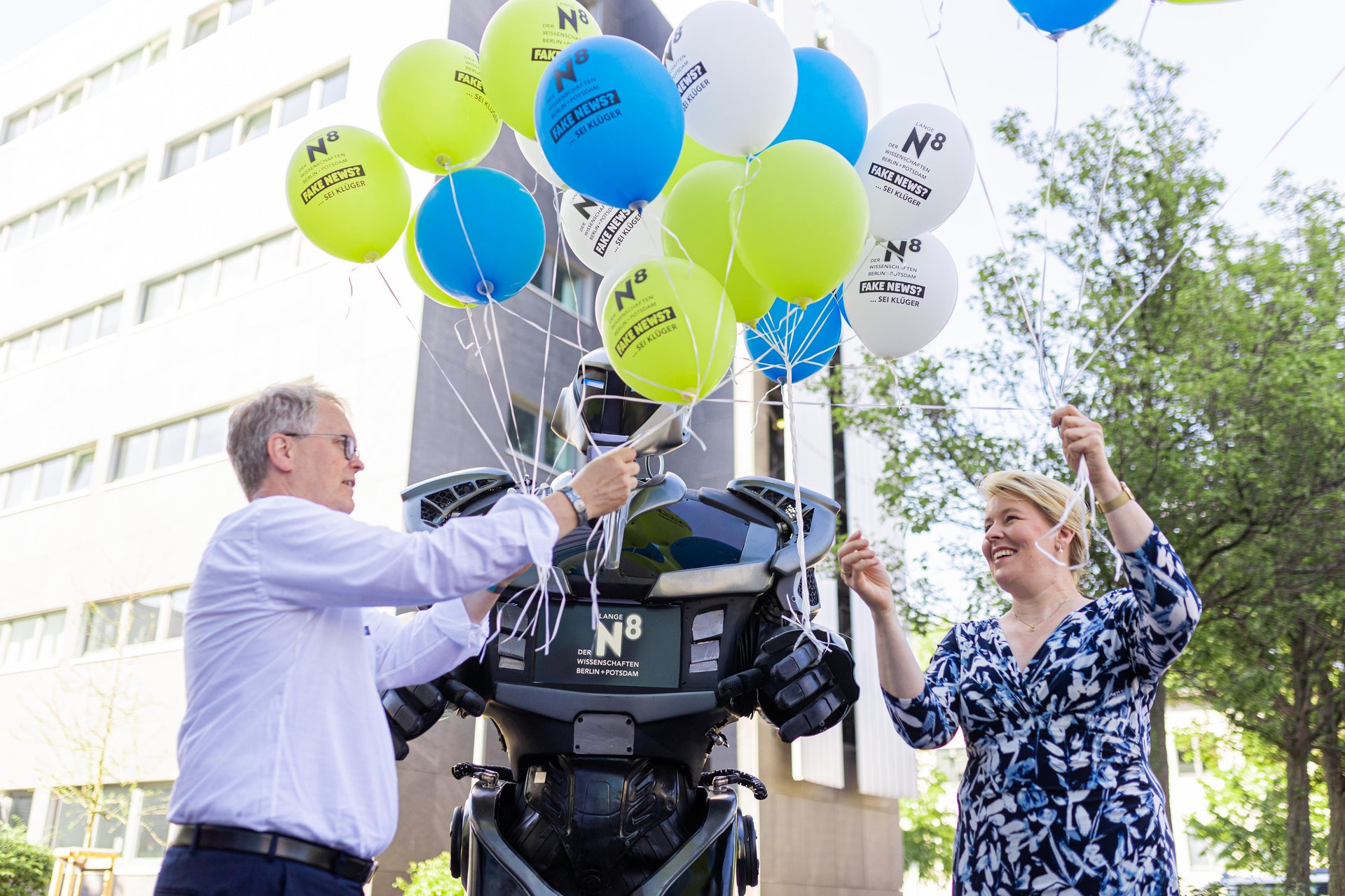 Bild-1 Die Regierende Bürgermeisterin Franziska Giffey und Prof. Dr. Ulrich Panne übernehmen vom Roboter Nox einen Strauss Luftballons.