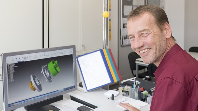 Ein Mann sitzt an einem Rechner und konstruiert ein Bauteil.  Kachel Vorschau