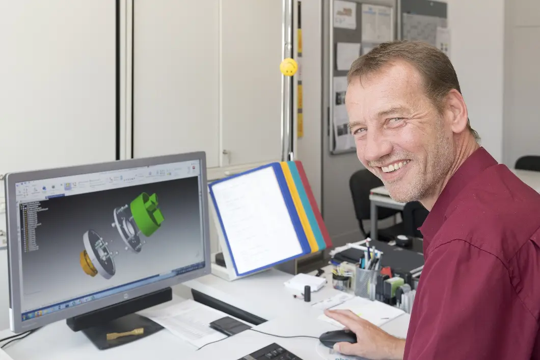 Ein Mann sitzt an einem Rechner und konstruiert ein Bauteil. 