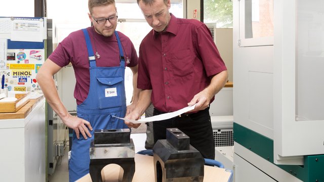 Zwei M&auml;nner kontrollieren zwei Bauteile.  Kachel Vorschau