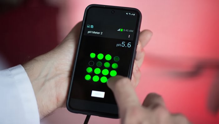 Ein BAM-Mitarbeiter hält ein Smartphone mit einem PH-Schnelltest in der Hand.