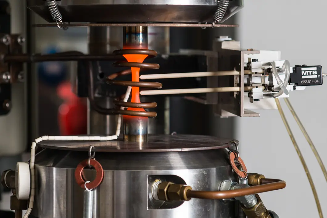 Und so sieht die der Versuchsaufbau im Detail aus: Die s&auml;ulenf&ouml;rmige Stahl-Probe wird - fest eingespannt - Druck und Zug ausgesetzt. Angelegte Sensoren messen die entstehenden Ver&auml;nderungen im Metall.