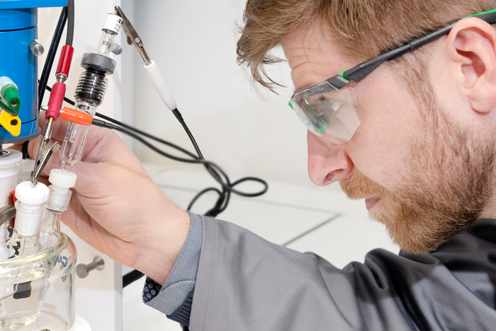 Forscher mit Schutzbrille vor Versuchsaufbau.