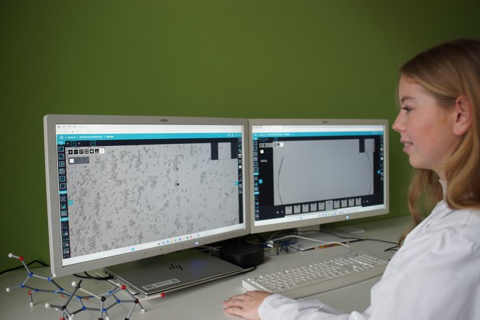 Eine Frau blickt auf zwei Computerbildschirme