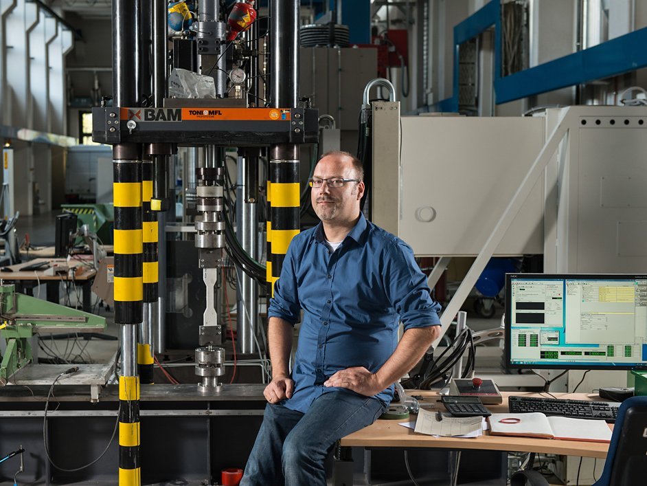 Dr. Dipl.-Ing Wolfram Schmidt in der Pr&uuml;fhalle der Abteilung Bauwerksicherheit. Eine seiner Betonproben wird auf Zug und Druck getestet.
