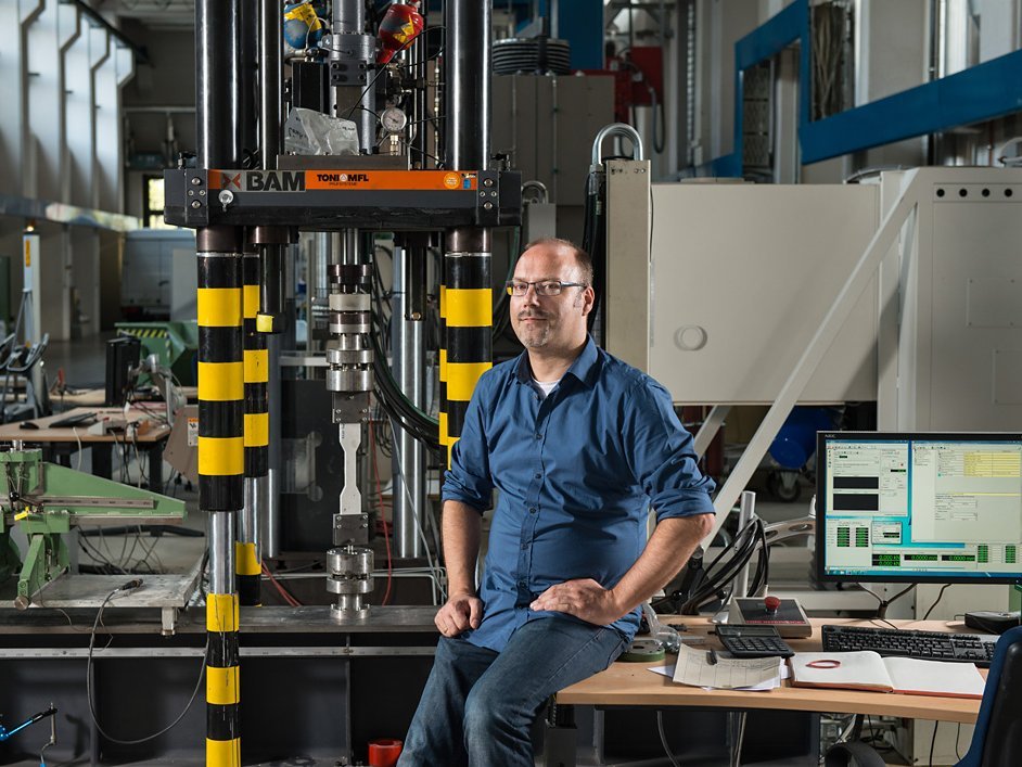 Dr. Dipl.-Ing Wolfram Schmidt in the test hall of the Department of Safety of Structures. One of his concrete samples is being tested for tension and pressure. 